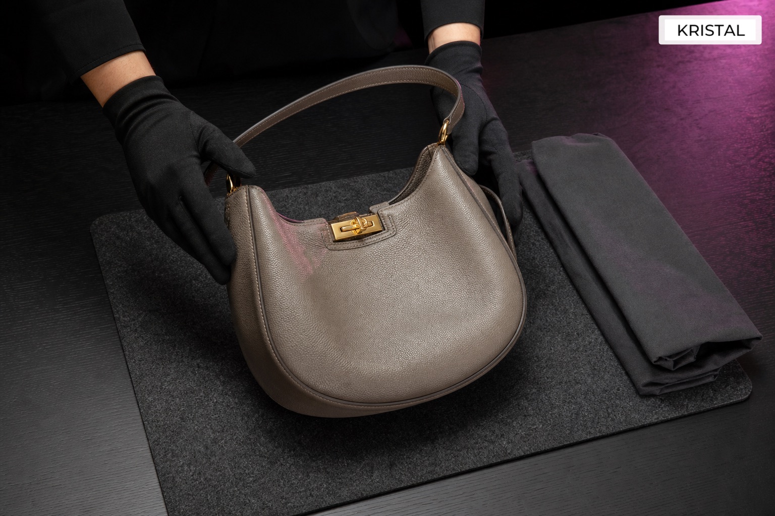 Gloved hands placing a shoulder bag on a graphite inspection mat beside a protective sleeve