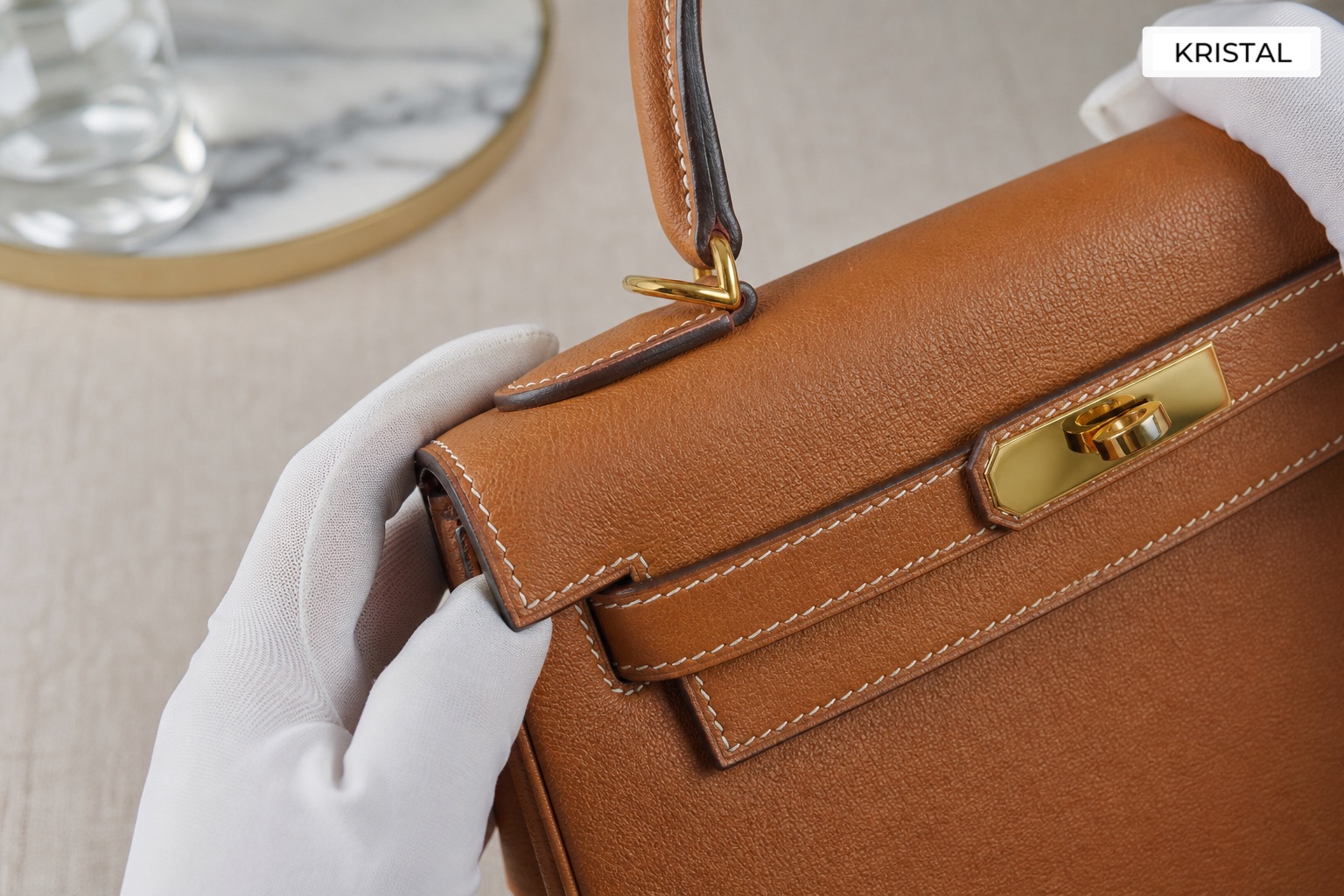 Close-up of structured top-handle luxury bag stitching, edge finish and hardware during assessment