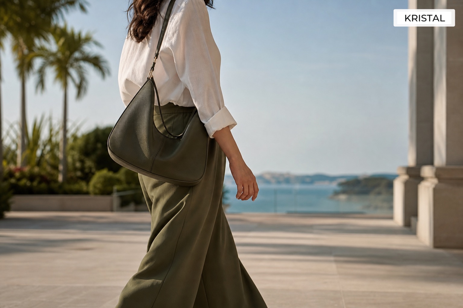 Person carrying a luxury shoulder bag in a tropical coastal setting