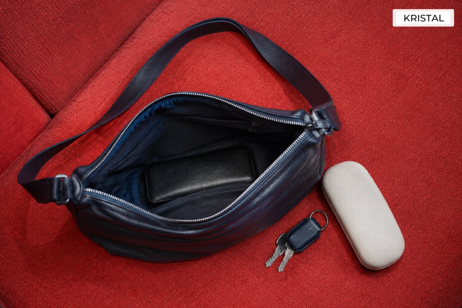 An open shoulder bag with a wallet, glasses case and keys for a daily capacity check