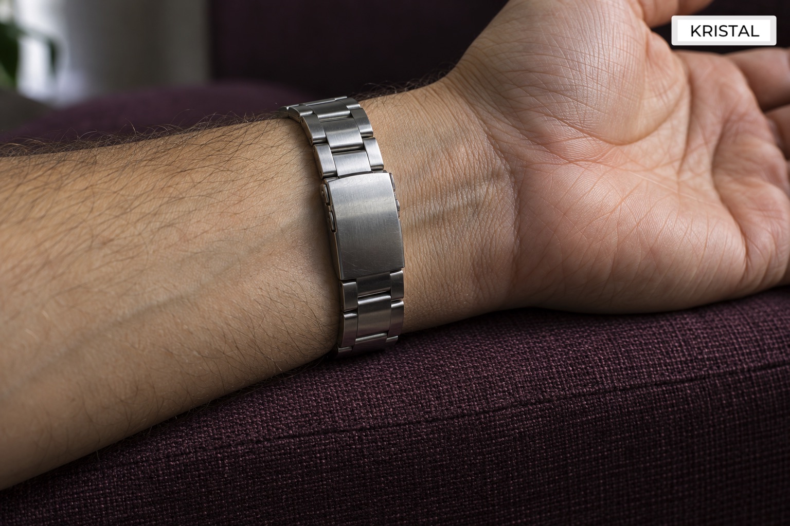 Underside view of a closed steel bracelet clasp resting against a wrist