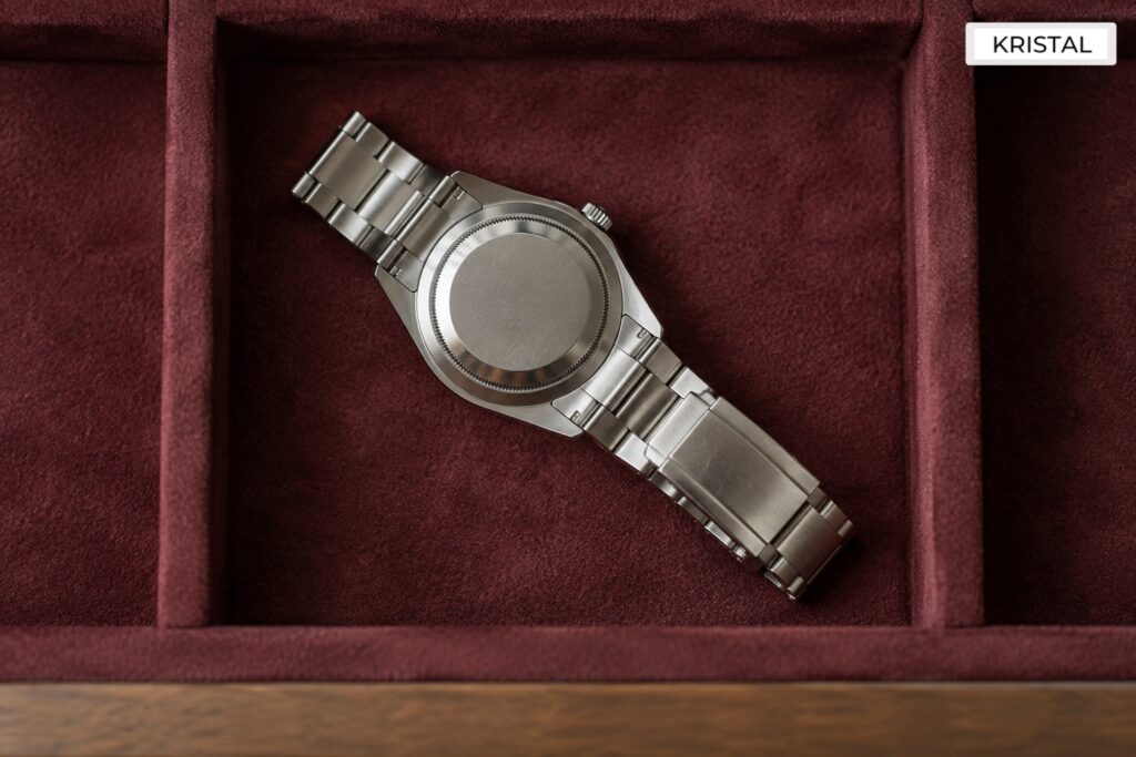 A stainless-steel watch resting unworn in a lined drawer.