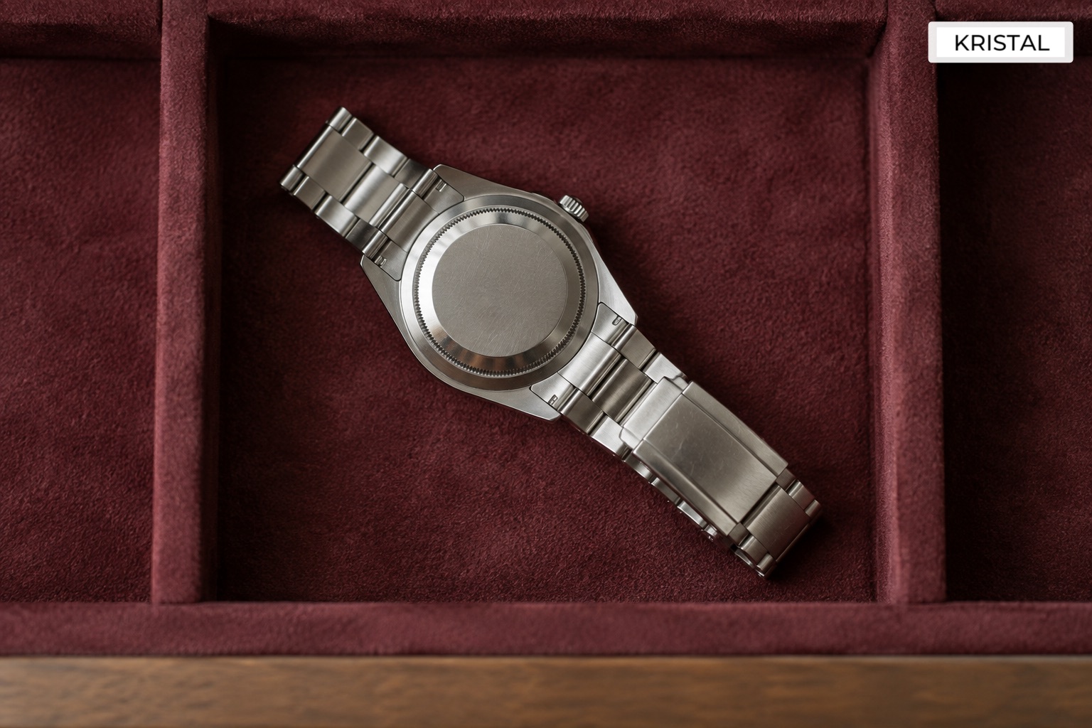 A stainless-steel watch resting unworn in a lined drawer.