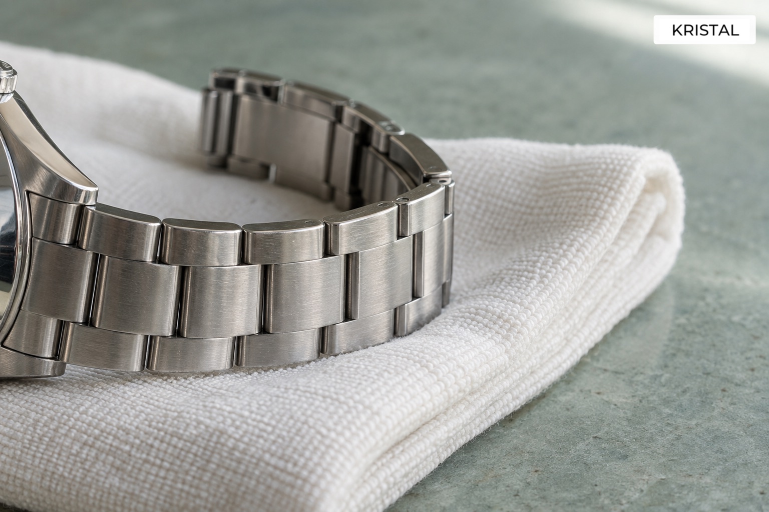 A dry metal watch bracelet resting on a clean folded cloth